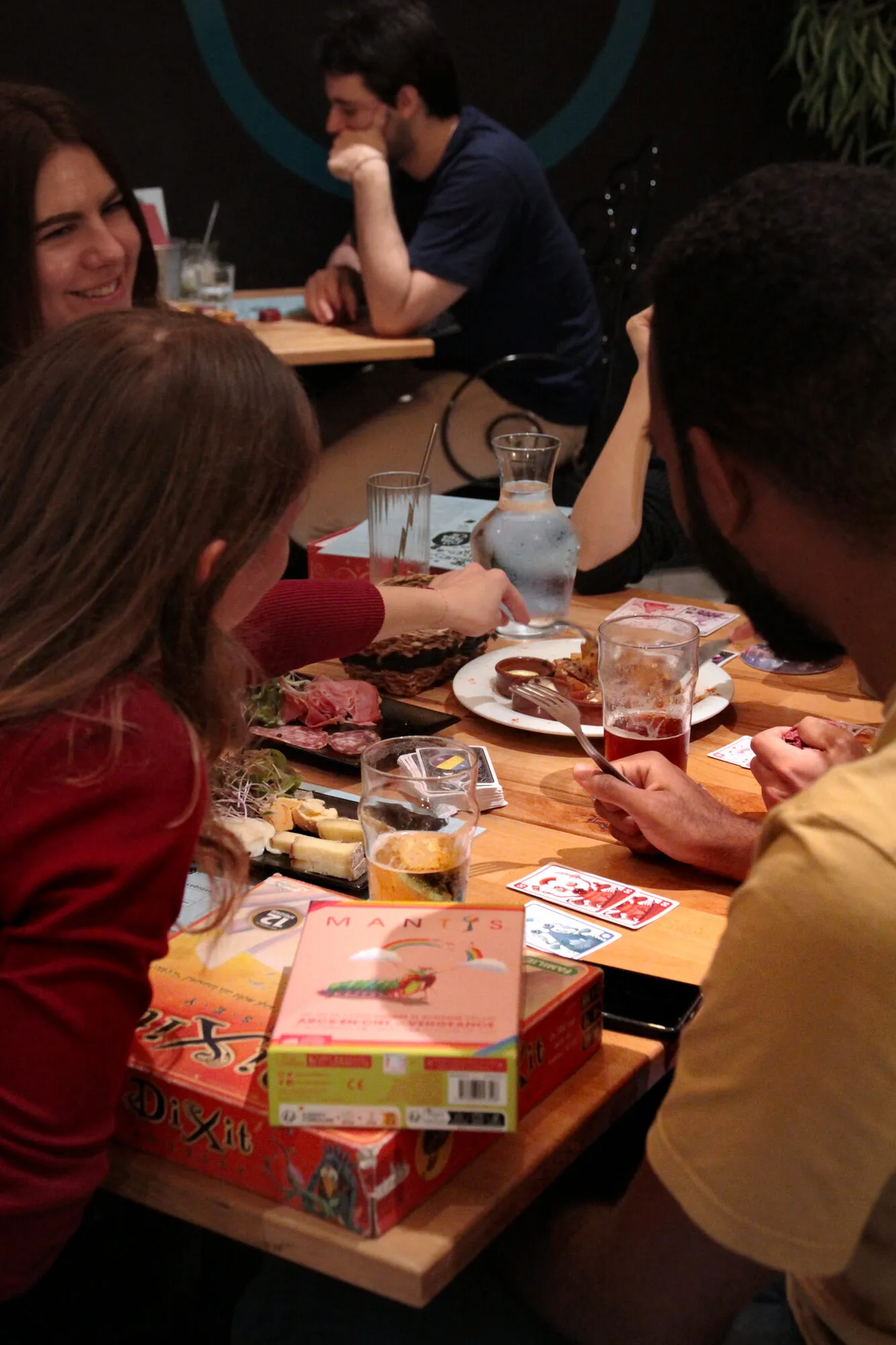 Une tablée entre amis, boîtes de jeux et assiettes à partager sur la table